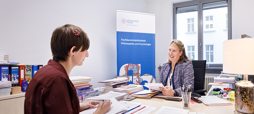 Die Leiterin der Fachbereichsbibliothek im Gespräch mit einer Kollegin. © Universität Wien / Joseph Krpelan